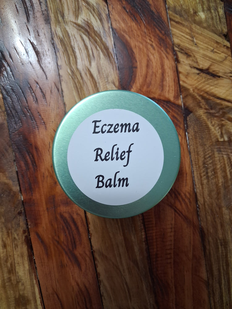 Mint-green metal balm tin with a round white label on a wood-grain background